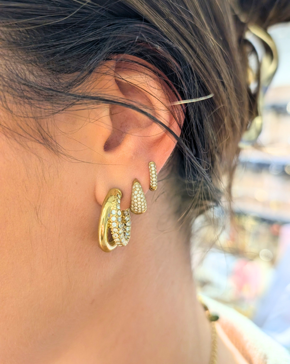 Drei aufeinander abgestimmte goldene Ohrringe mit funkelnden Kristallen in verschiedenen Formen - ein moderner Ohrschmuck von Patrizia Ljubljana.