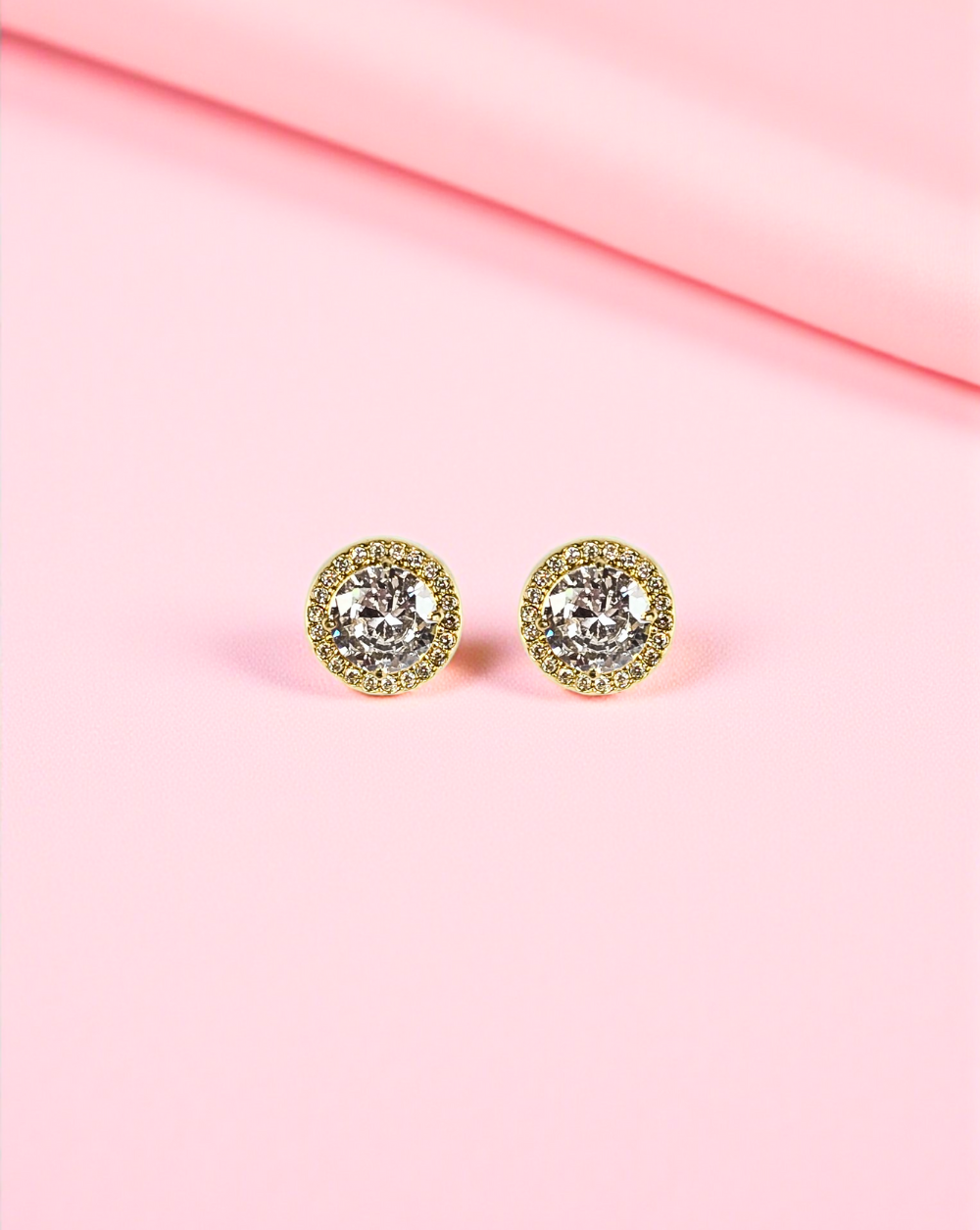 Goldene Ohrringe mit Edelstahlkristallen auf rosa Hintergrund - Trgovina Patrizia Ljubljana.