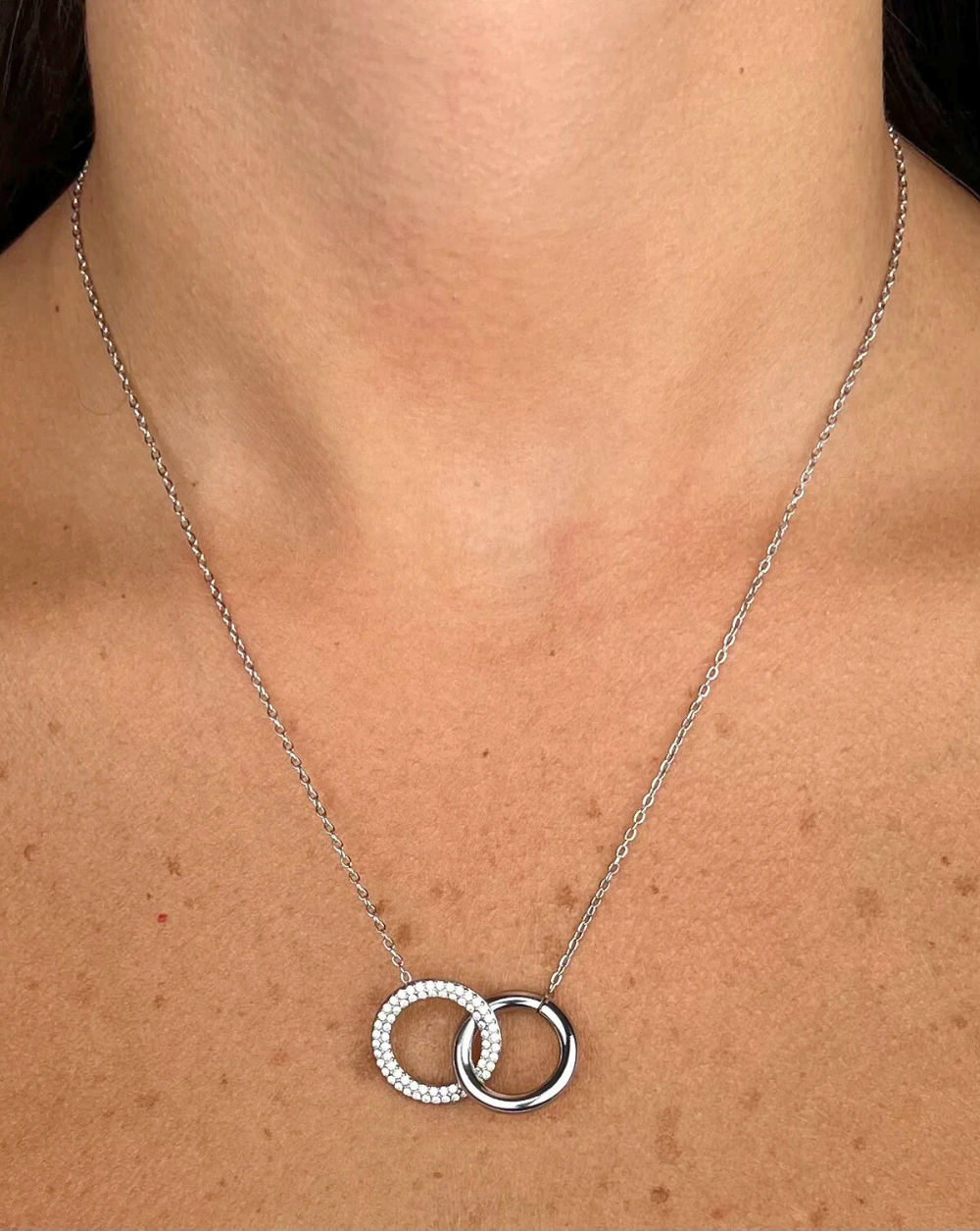 Verižica PAVÉ DUO iz nerjavečega jekla z dvema prepletenima pavé krogoma, prikazana na vratu modela – Trgovina Patrizia Ljubljana.