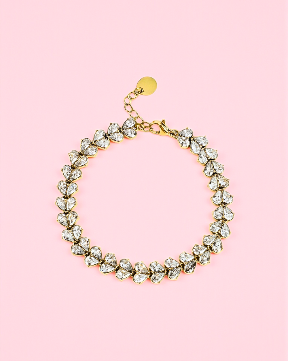 Zlata zapestnica iz nerjavečega jekla v obliki cvetnih listov na rožnatem ozadju – Trgovina Patrizia Ljubljana.