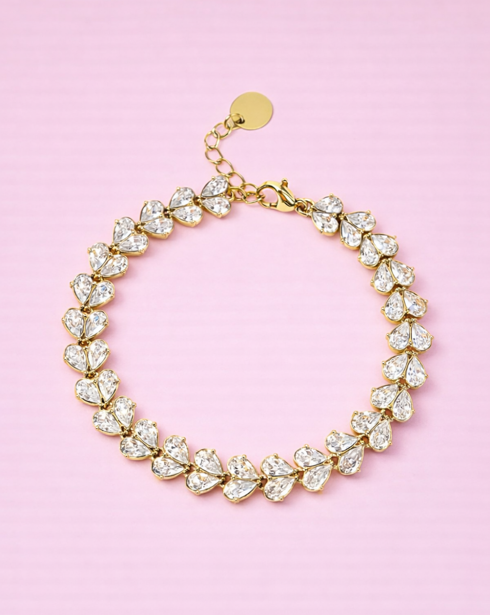 Zlata zapestnica iz nerjavečega jekla v obliki cvetnih listov na rožnatem ozadju – Trgovina Patrizia Ljubljana.