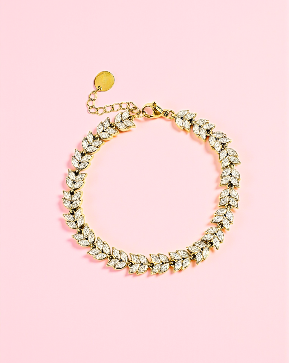 Zlata zapestnica iz nerjavečega jekla v obliki cvetnih listov na rožnatem ozadju – Trgovina Patrizia Ljubljana.