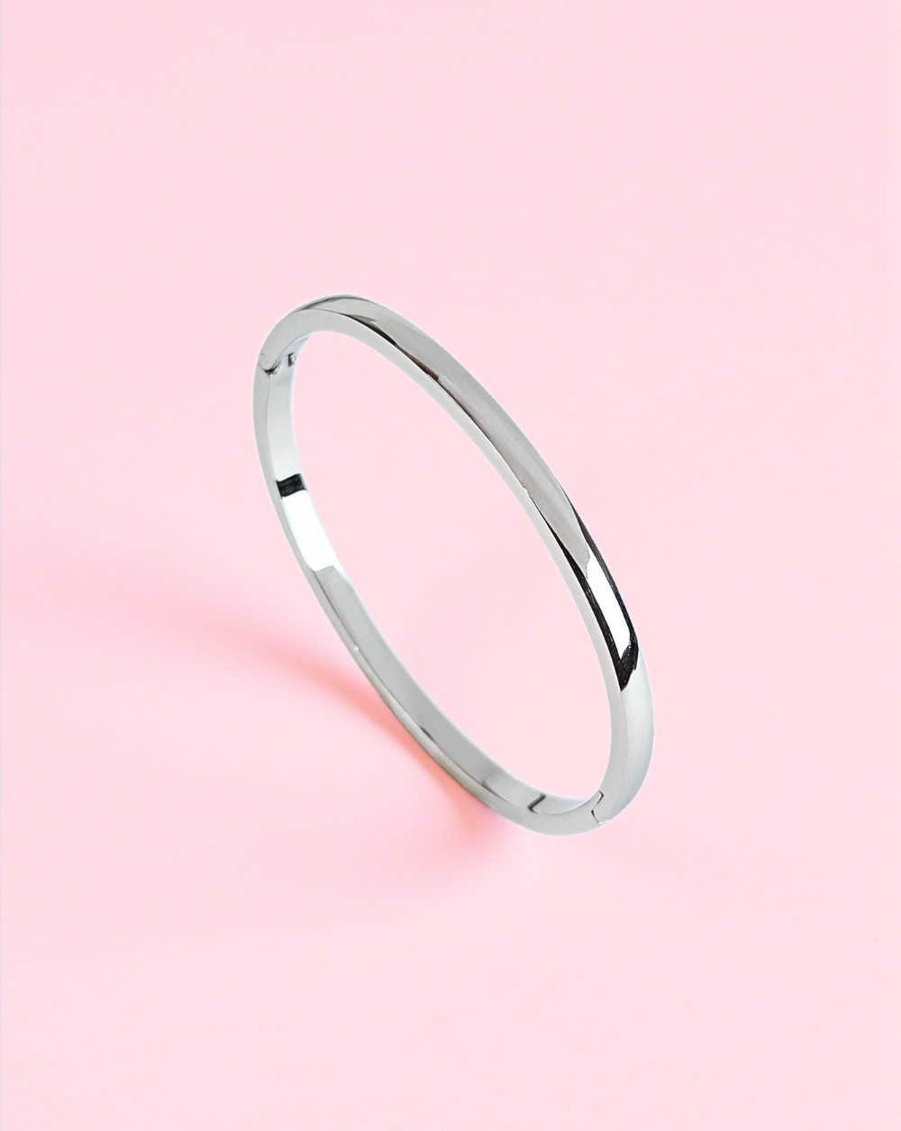 Srebrna bangle zapestnica iz nerjavečega jekla na rožnatem ozadju – Trgovina Patrizia Ljubljana.