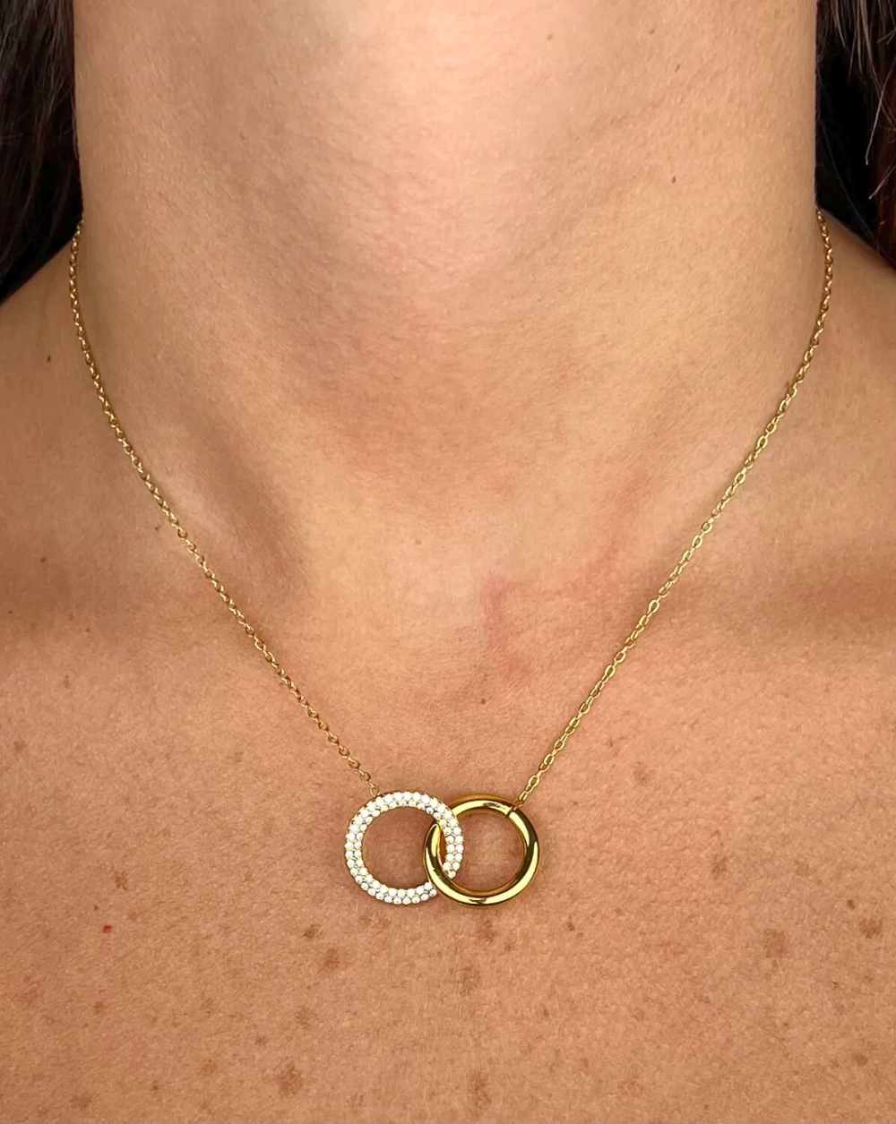 Verižica PAVÉ DUO CIRCLES iz nerjavečega jekla z dvema prepletenima pavé krogoma, prikazana na vratu modela – Trgovina Patrizia Ljubljana.