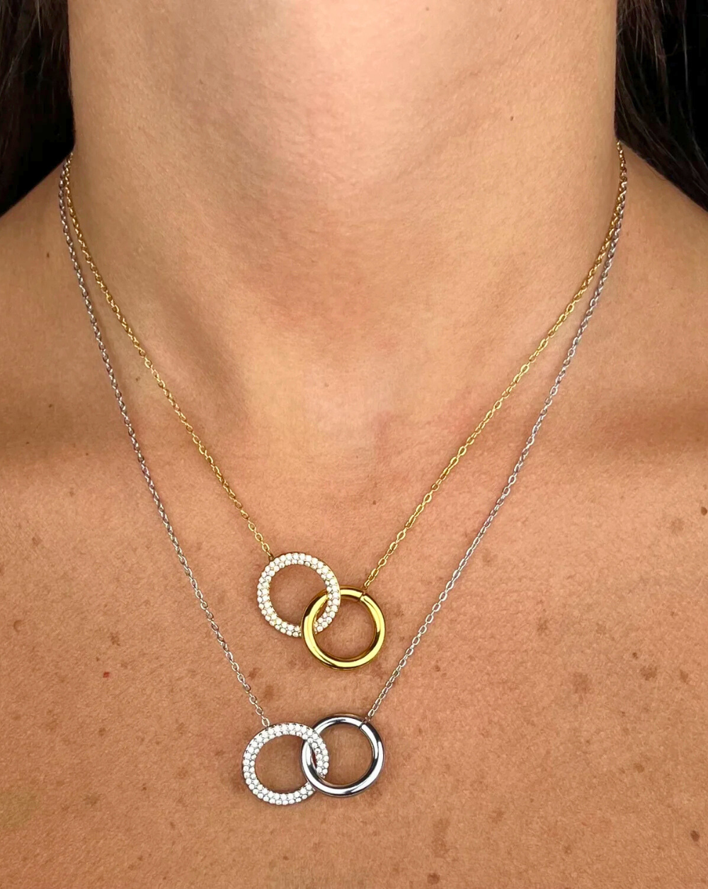 Verižica PAVÉ DUO CIRCLES iz nerjavečega jekla z dvema prepletenima pavé krogoma, prikazana na vratu modela – Trgovina Patrizia Ljubljana.