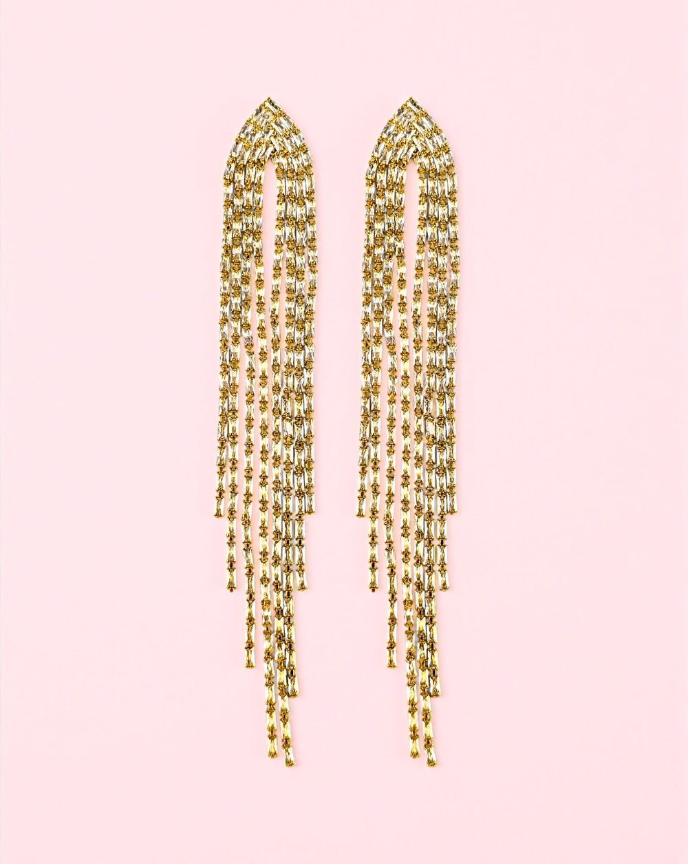 Dolgi zlati viseči uhani iz rodirane kovine z bleščečimi detajli na rožnatem ozadju – Trgovina Patrizia Ljubljana.