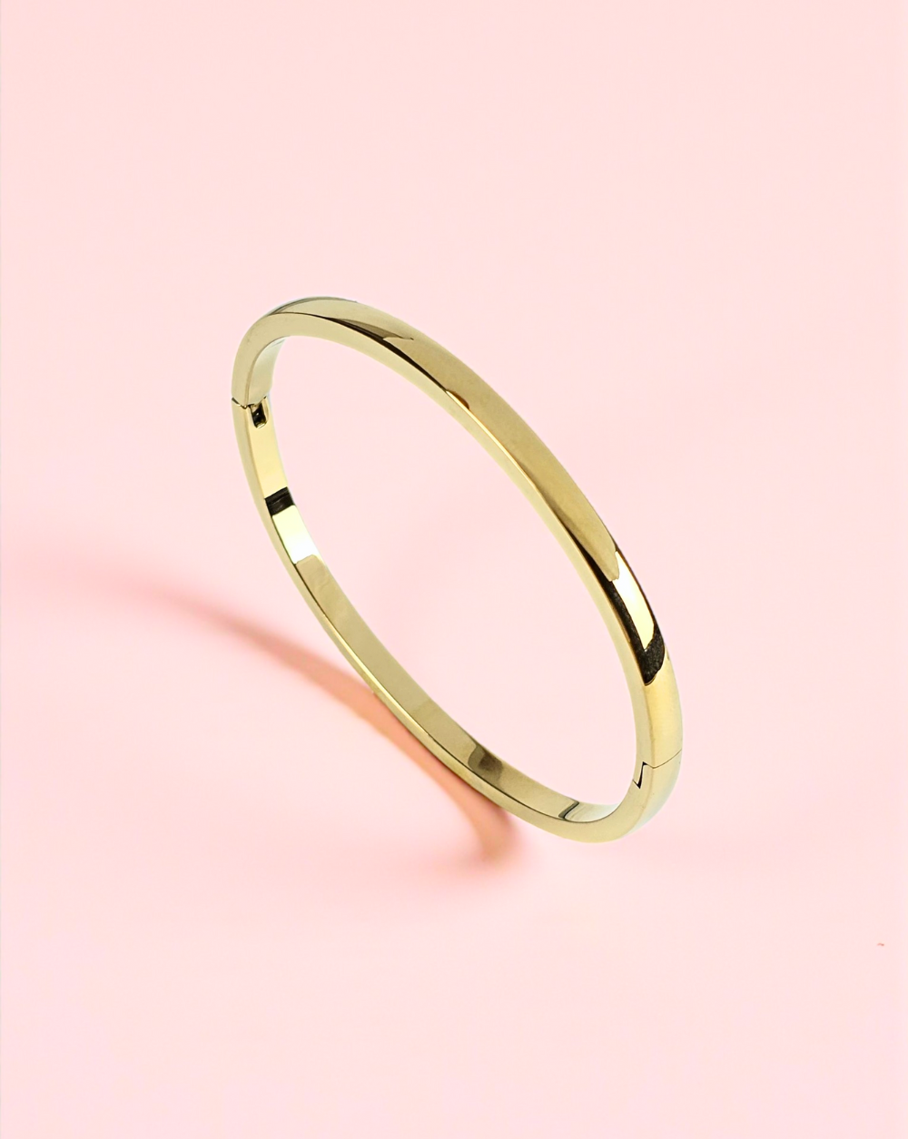 Srebrna bangle zapestnica iz nerjavečega jekla na rožnatem ozadju – Trgovina Patrizia Ljubljana.