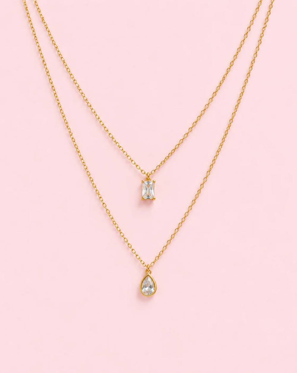 necklace 's CRYSTAL DUO stainless steel necklace with two chains of different lengths, a rectangular crystal pendant, and a teardrop-shaped crystal— Trgovina Patrizia , Ljubljana.