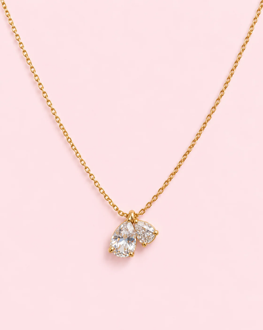 Gold necklace CRYSTAL DUO, made of stainless steel with two transparent crystals—a larger teardrop-shaped one and a smaller round one— Trgovina Patrizia , Ljubljana.