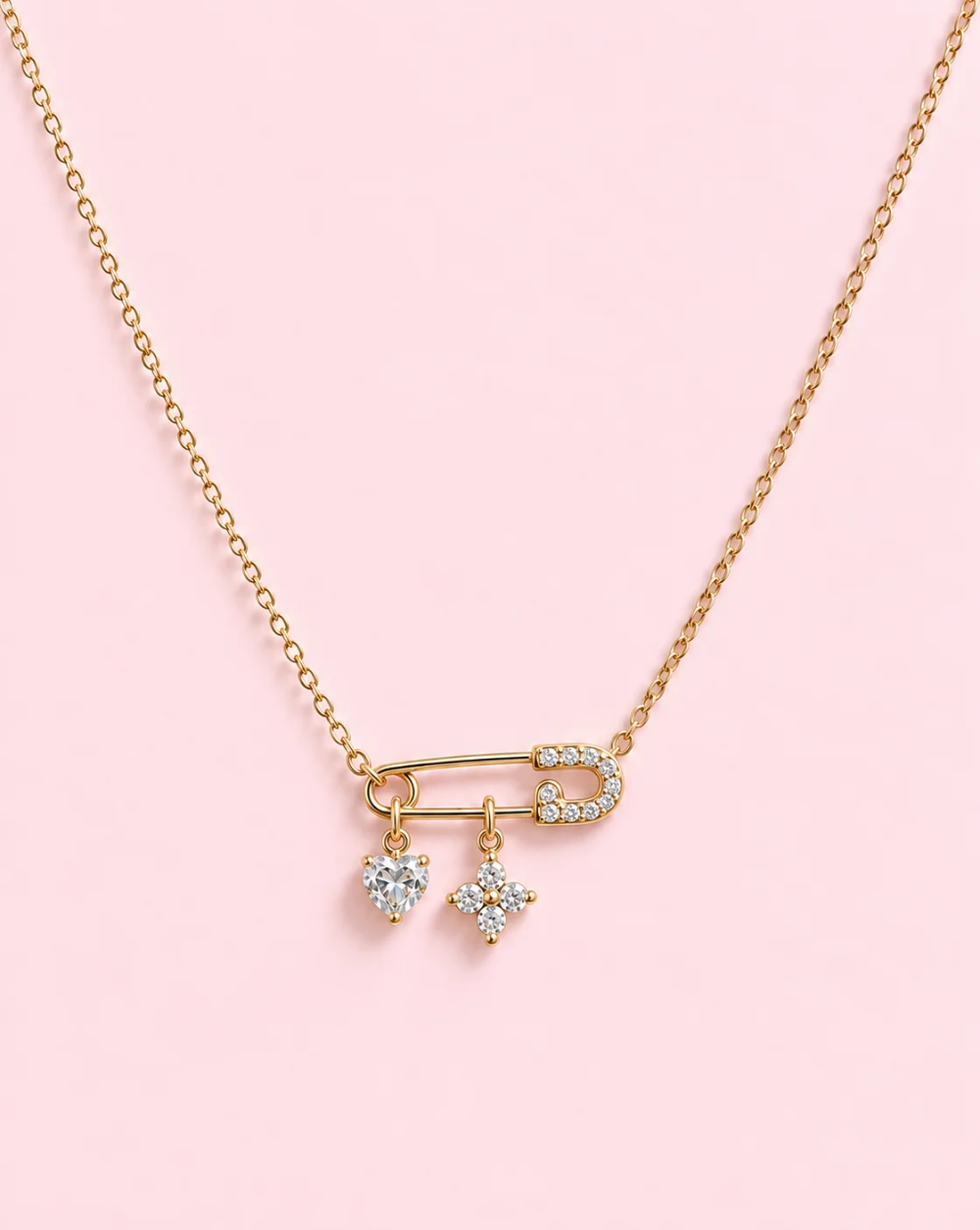 Gold necklace ICONIC PIN made of stainless steel with a safety clasp, adorned with crystals and featuring two dangling charms in the shape of a heart and a star— Trgovina Patrizia , Ljubljana.